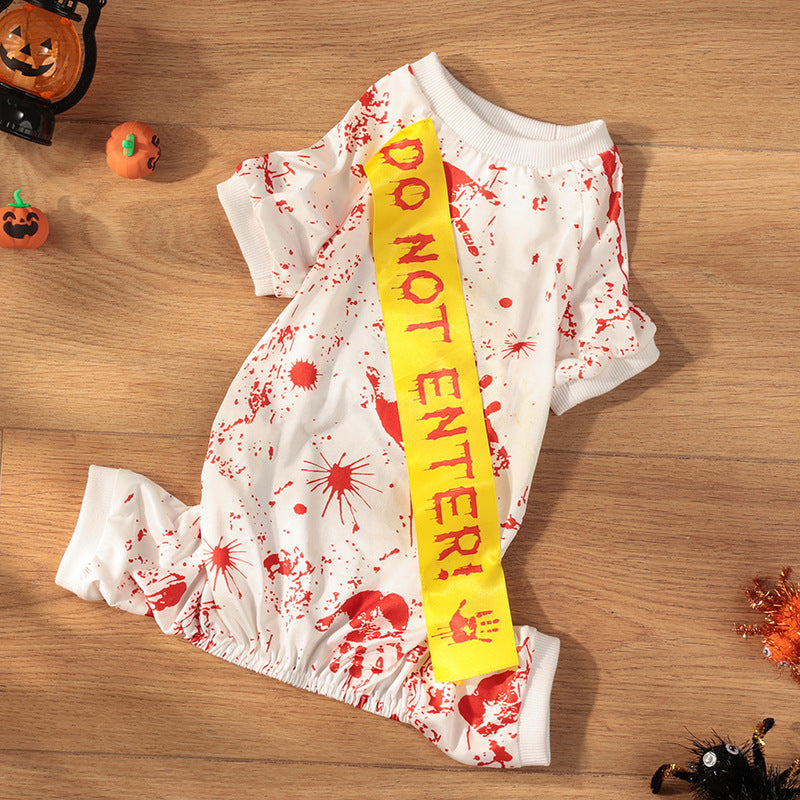 White dress with red splatter design and yellow 'Do Not Enter!' sash on a wooden surface with Halloween decorations.