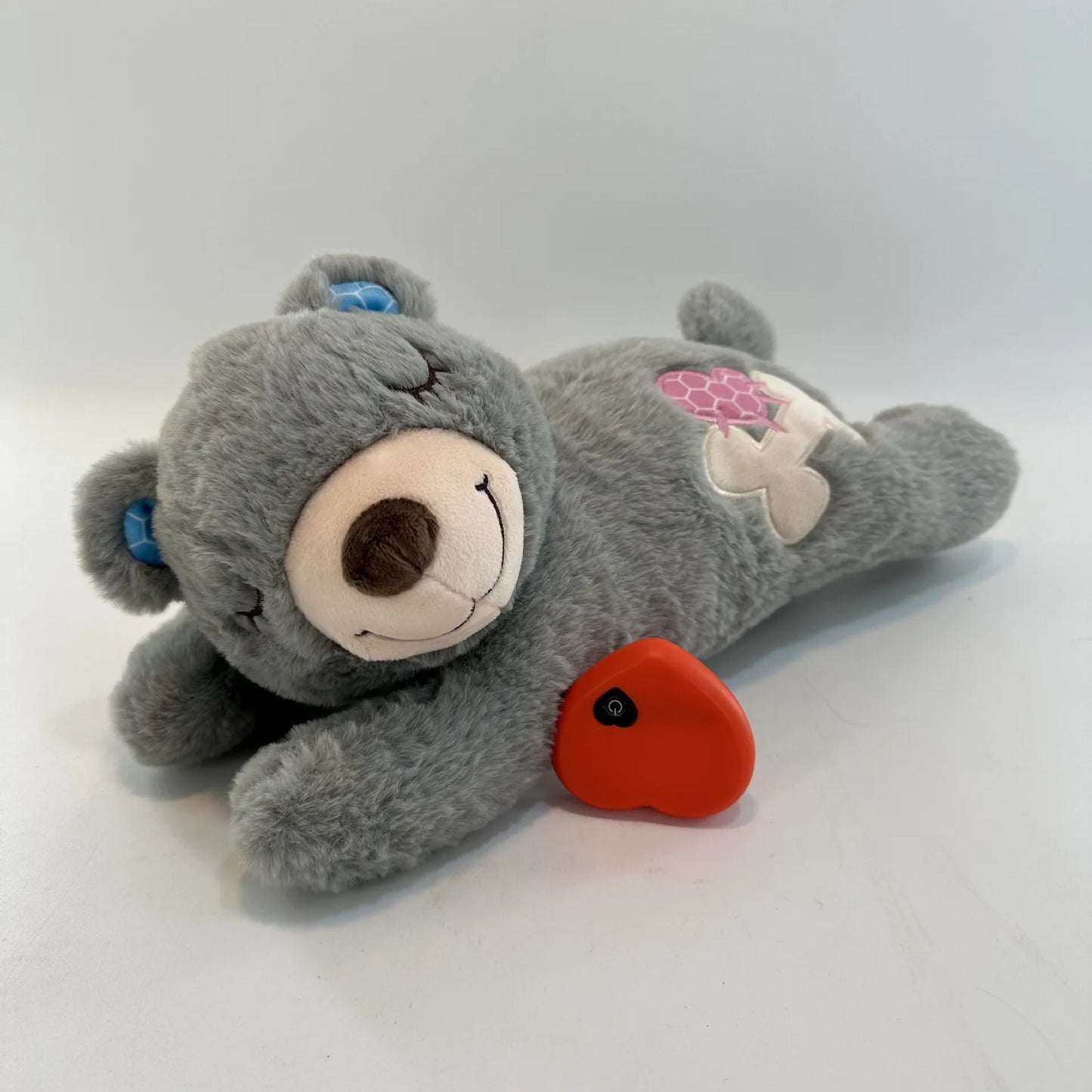 Gray teddy bear plush toy with a red heart on a white background