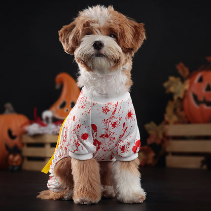 Dog wearing a Halloween-themed outfit with blood splatter design in front of pumpkins.