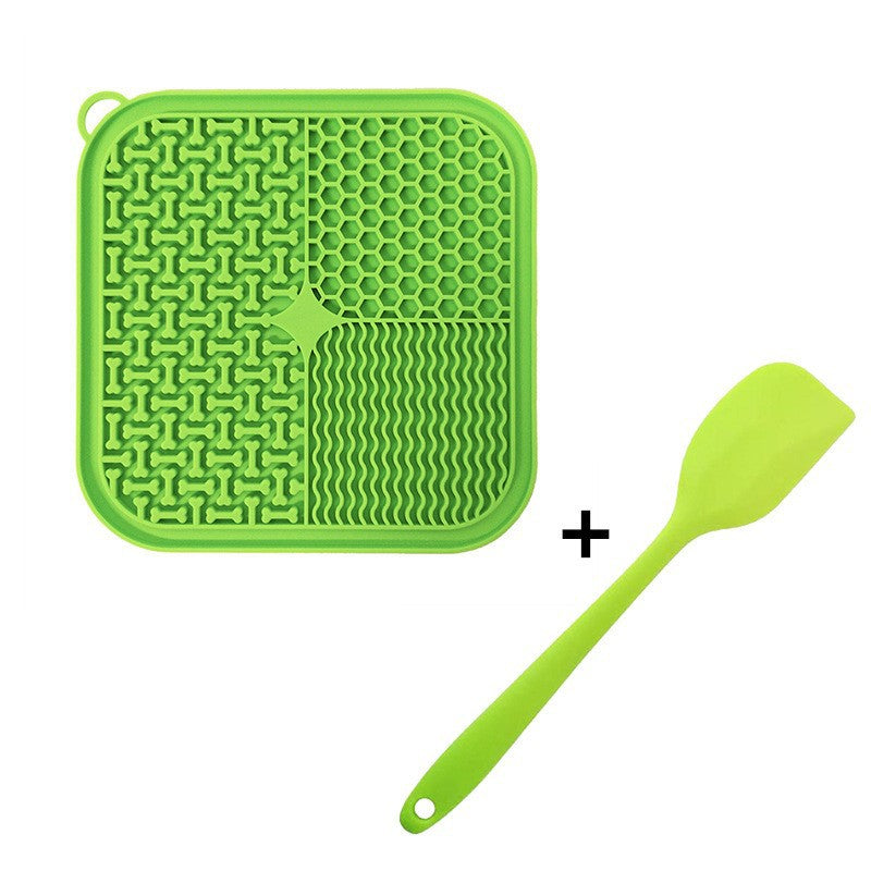 Green silicone Dog Licking Mat Slow Feeder and spatula on a white background