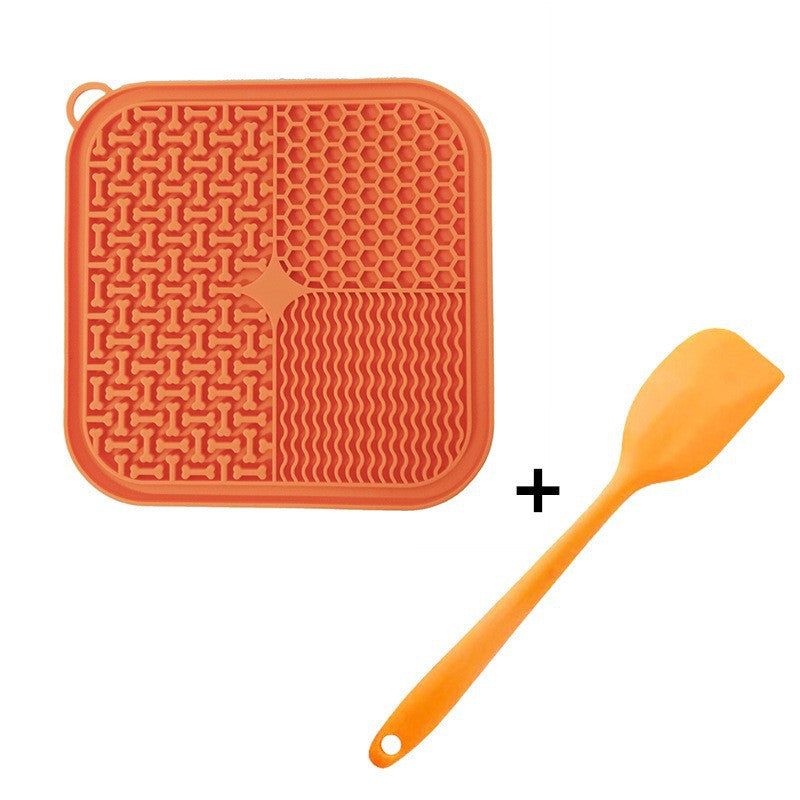 Orange silicone Dog Licking Mat Slow Feeder and spatula on a white background