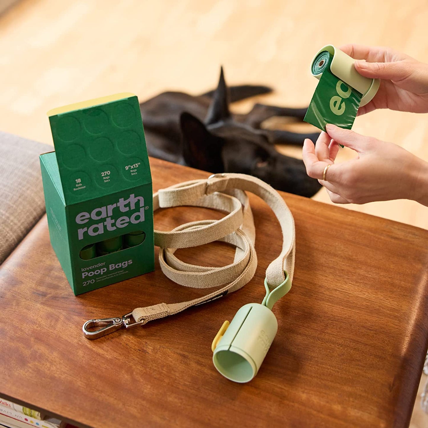 Earth Rated dog waste bags packaging with a leash and poop bag dispenser on a wooden surface.