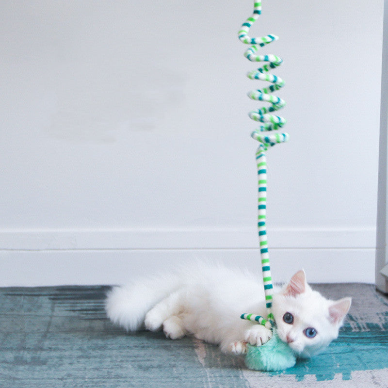 White cat playing with a striped Interactive Cat Hanging Toy on a blue rug.