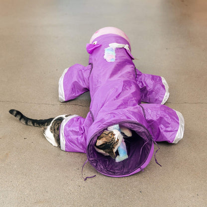 Cat inside a purple snowsuit on a beige floor