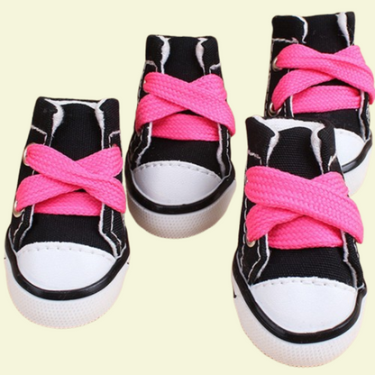 Small dog wearing four canvas sneakers, perfectly fitted on each paw, standing on a sidewalk — photorealistic image focused on pet shoes black variant